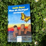 Buch „Wenn die Nachtigall verstummt“ von Isolde Heyne auf einer Wiese mit Gänseblümchen und Klee liegend.